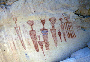 A picture of a rock with some red painted figures. 