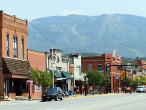 A view of the district from across the street with different kinds of buildings and mountains in the background.