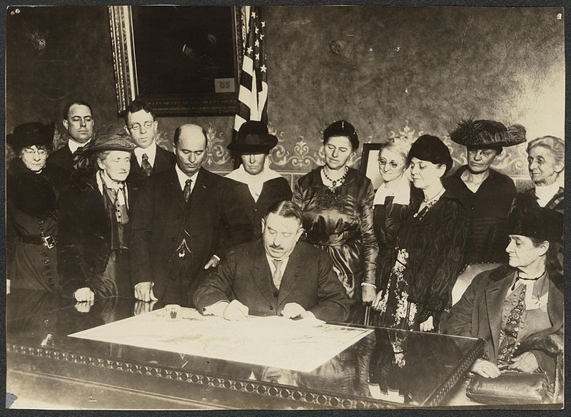 Governor signing bill with men and women around his desk