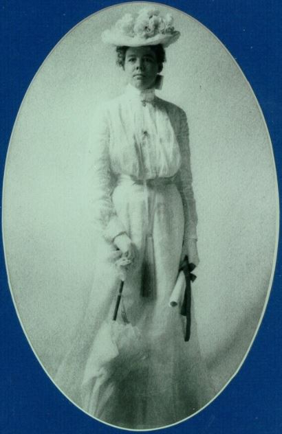 Photo portrait of a well-dressed woman from 1902, with hat, parasol, and long dress