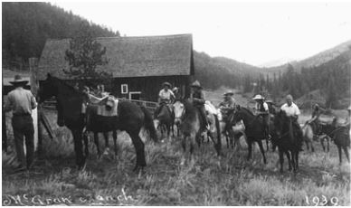 Photo of about a dozen cowboy hat-wearing guests of the McGraw Ranch saddling up their horses and getting ready for a trail ride.