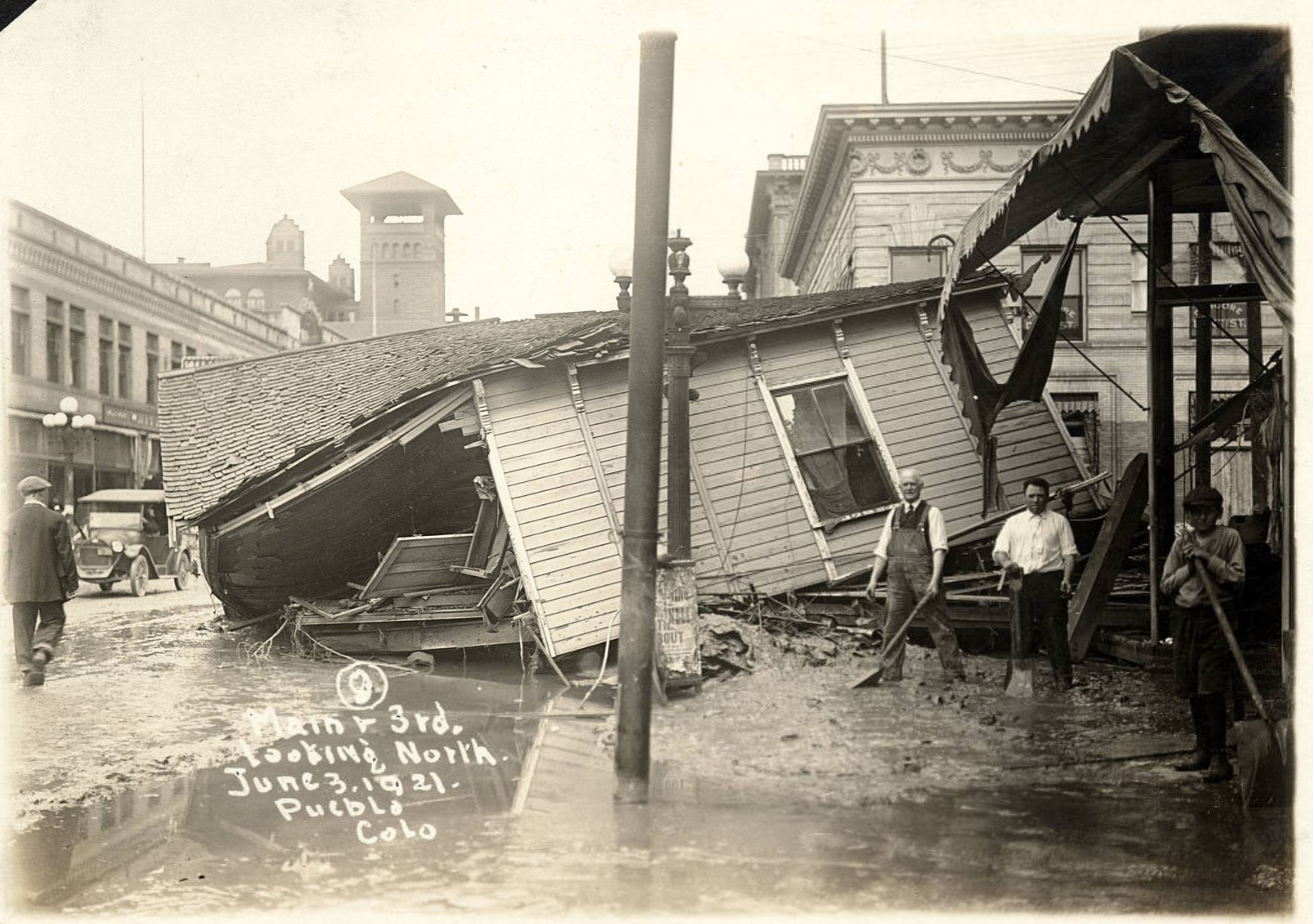 Shoveling mud by destroyed house after 1921 Pueblo Flood
