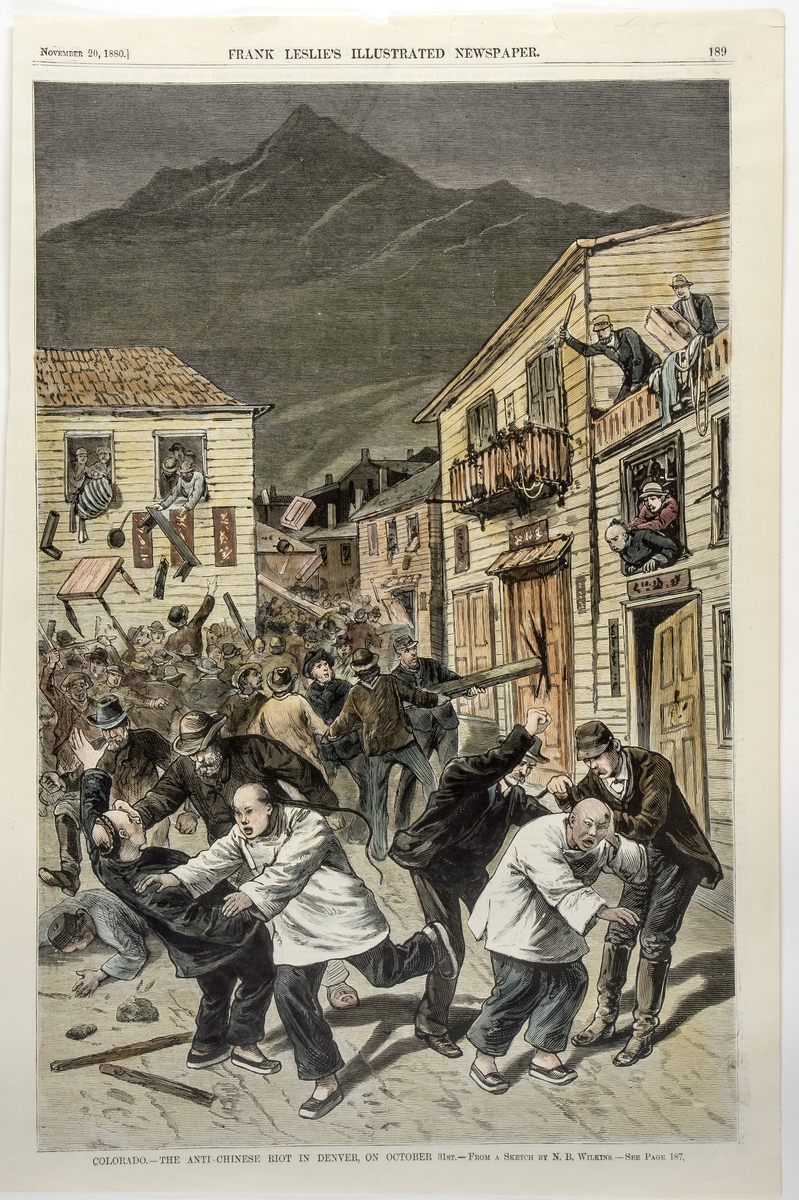 Image of a newspaper illustration of the anti-Chinese riot in Denver in 1880. In the foreground, white western-looking men are striking Chinese men. One Chinese man is holding his head where he has been hit, while another is running away and yet another is lying face-down on the ground. In the background, rioters in building windows are throwing furniture out of the windows and fighting with other Chinese men. A group of rioters are breaking down the doors of an establishment using a long wooden post.