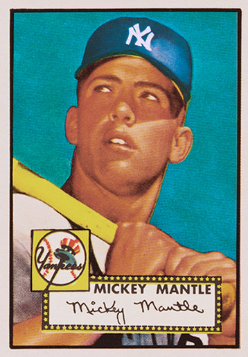 Photo of the famous Mickey Mantle baseball card, produced by Topps. It features a thin white border, and the image inset is of a young player resting his bat on his right shoulder while he looks off in the distance to the right. He is wearing a dark blue cap with the New York Yankees logo in white, and a white top. He is holding the bat with both hands around the handle. The caption has the Yankees team logo, and "Mickey Mantle" spelled in block lettering above his signature, surrounded by a marquee border.