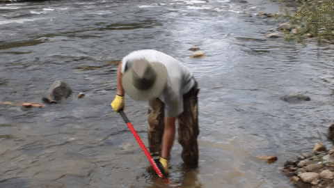 Gold panner shoveling river bed into pan