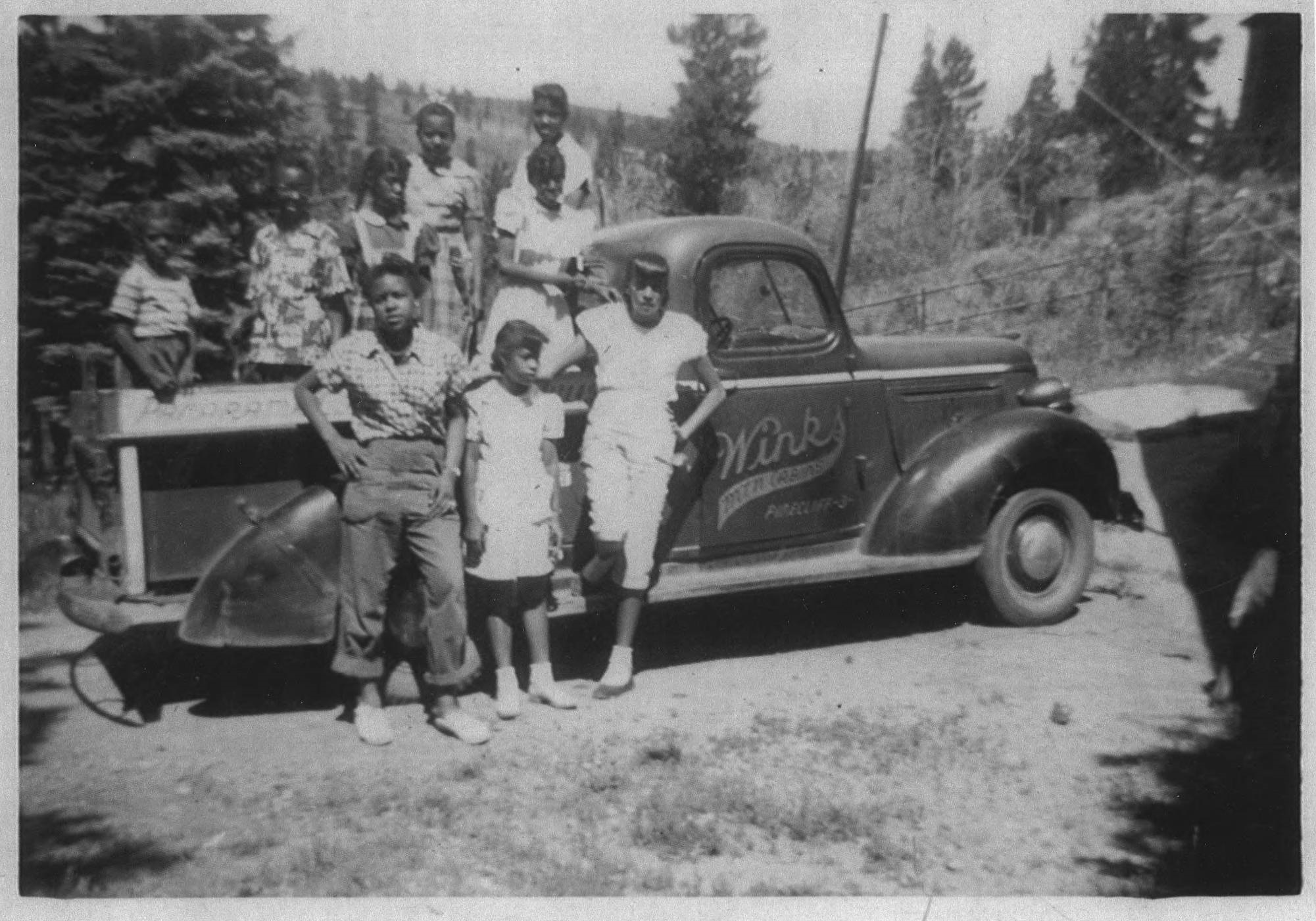 Children stand in and in front of a “Winks Mountain Cabins” pickup truck in the 1950s