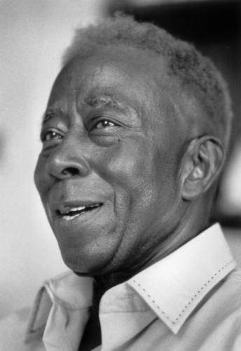 A black and white portrait of an African American man in a high collared shirt.