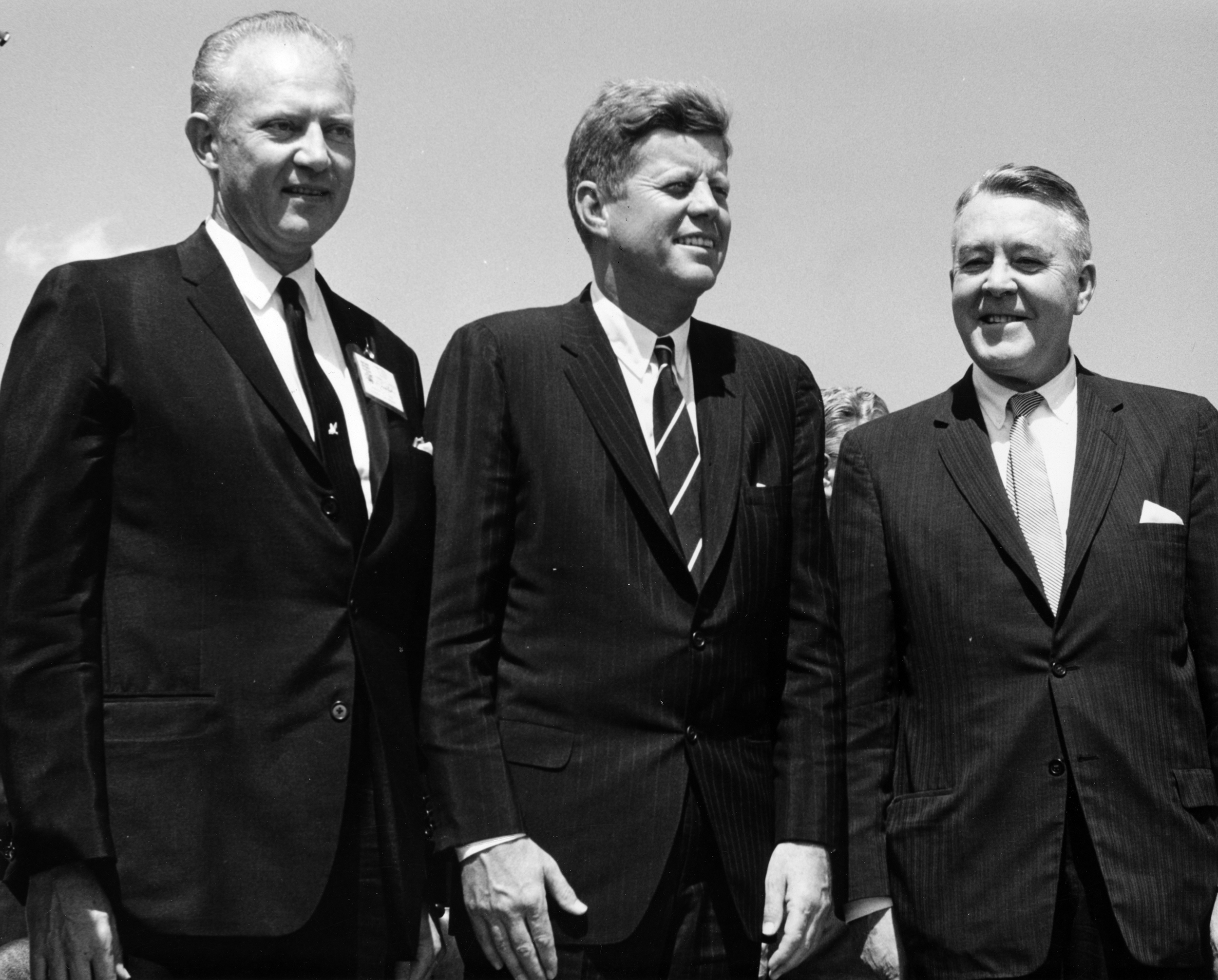 President Kennedy, Governor Stephen McNichols, and U.S. Senator John Carroll all stand together in suits.