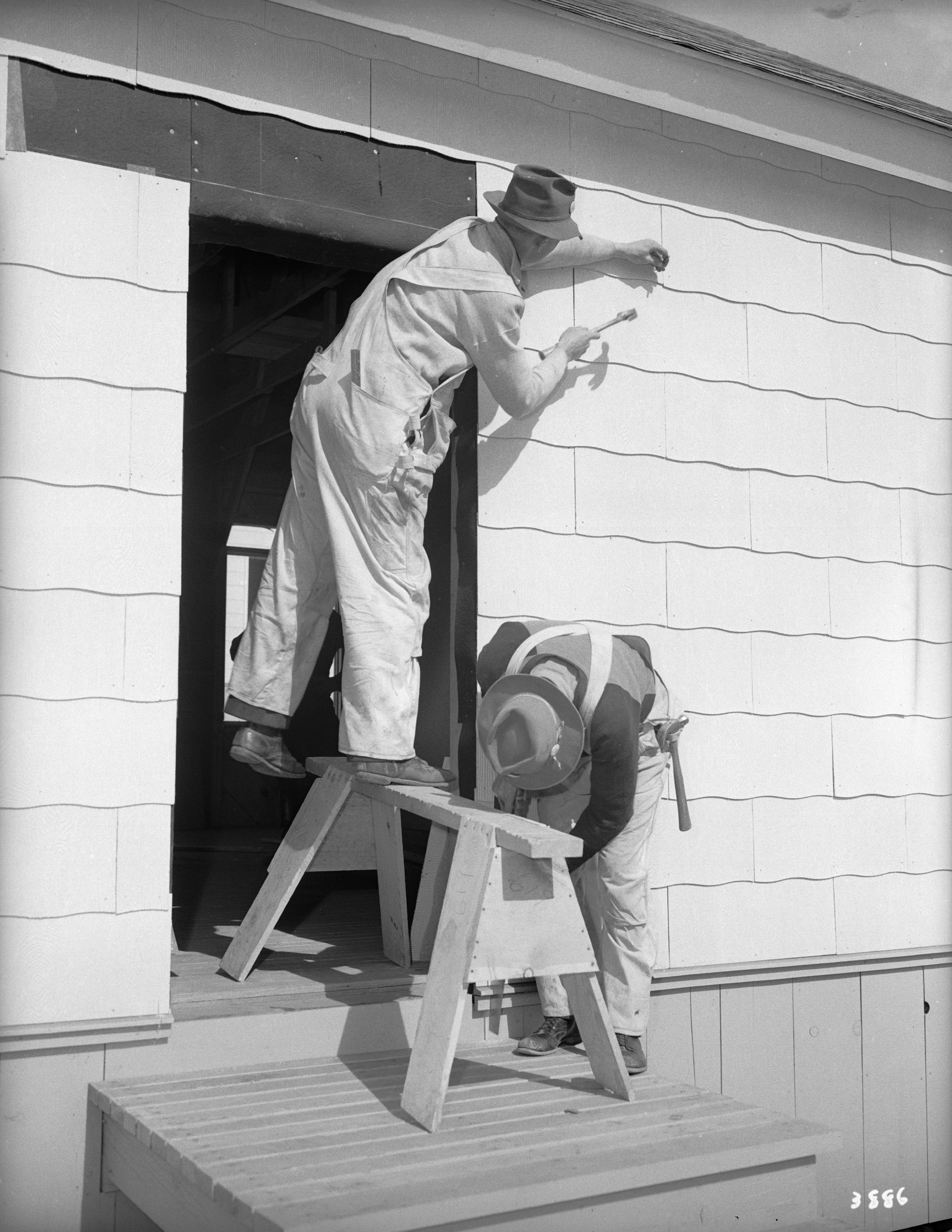 Two men in a doorframe, hammering pieces of wood into place.