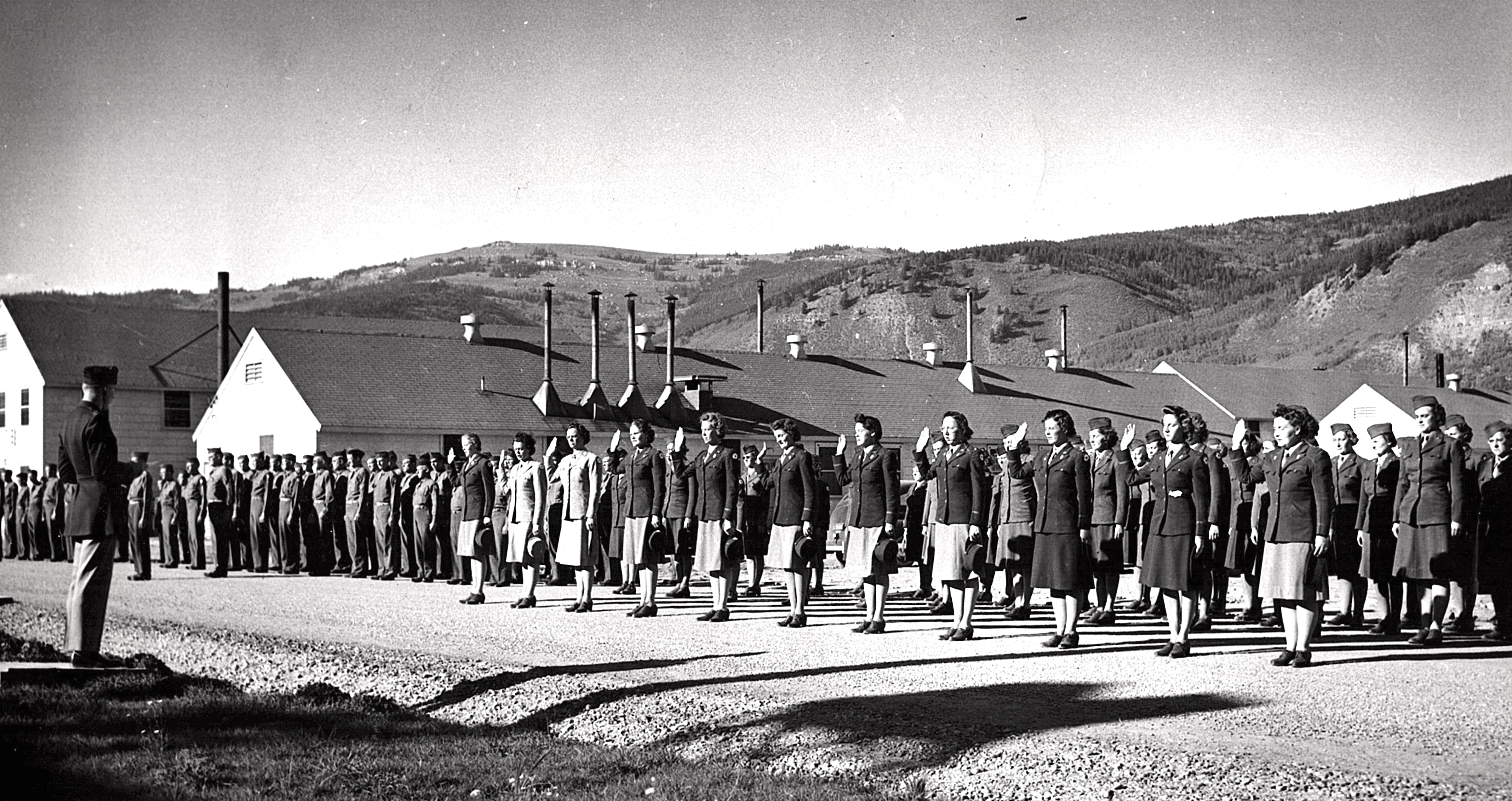 A group of women in uniform standing in formation, saluting an officer.