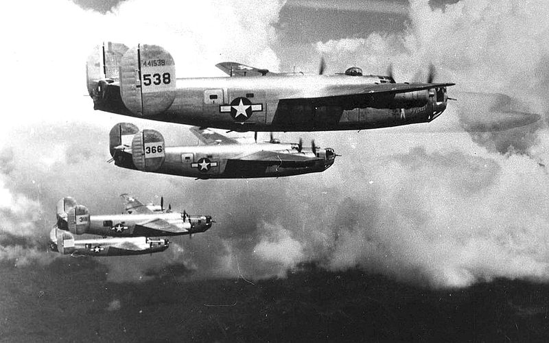 A squadron of four World War 2 era bomber planes flying in formation.