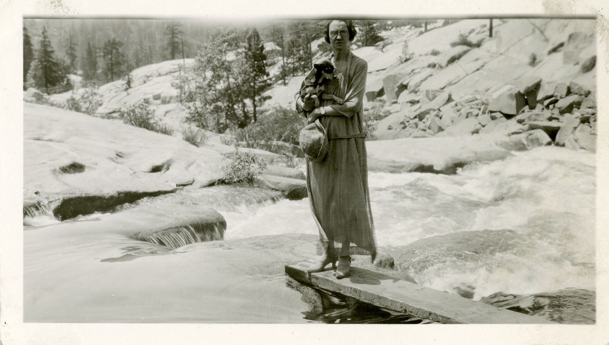Laura Evans holding her dog, Mister Pimp Powers, while standing near a river. 