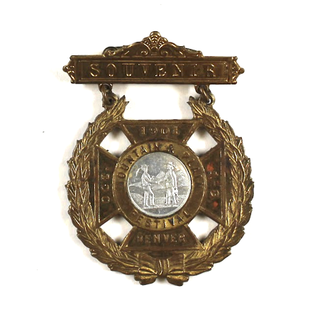 A brass souvenir badge from the 7th annual Festival of the Mountain and Plain.