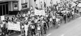 Large group of people with protest signs marching in Denver's 1981 Pride Parade