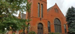 A photograph of the Grace Commons Church, a brick church, formerly First Presbyterian Church of Boulder.