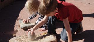 Children try their hand at grinding corn with a mano and metate.
