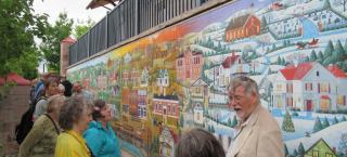Tom Noel giving lecture next to mural