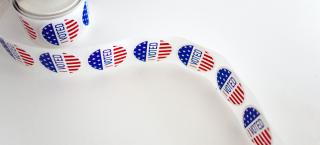 Stock photo of a roll of red, white, and blue round stickers that say "I Voted"