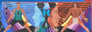 A colorful mural depicting an eagle whose wings form the faces of Chicana women. On one side is a modern chicano athlete, on the other side is an Indigenous person participating in a ritual.