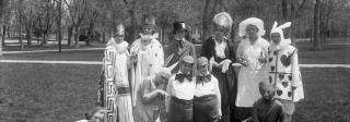 A group of individuals dressed as various characters from Alice in Wonderland, including Alice, Tweedle-Dee and Tweedle-Dum, the Queen of Hearts, the Mad Hatter, and the White Rabbit.