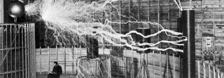 A multiple exposure picture of Tesla sitting next to his "magnifying transmitter" generating millions of volts. The 7-metre (23 ft) long arcs were not part of the normal operation, but only produced for effect by rapidly cycling the power switch.