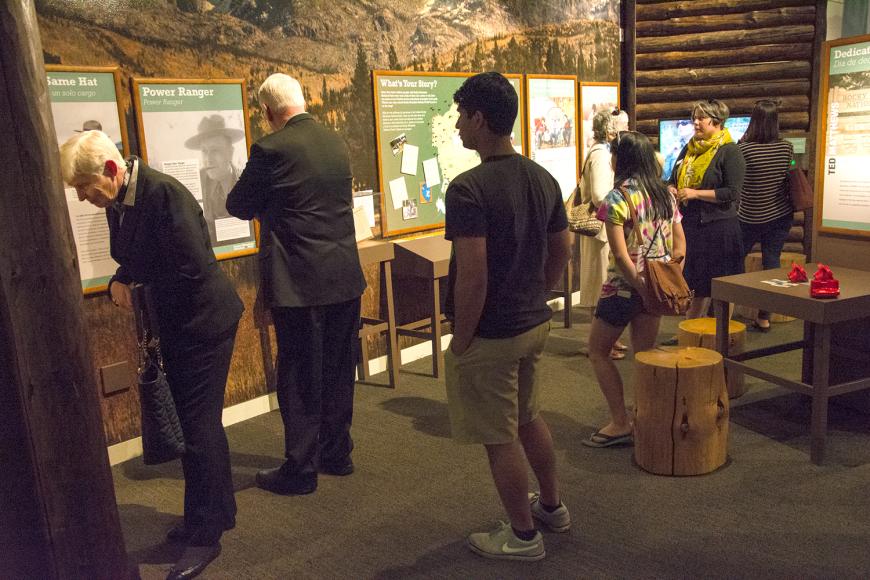People engaging with various RMNP display cases and material. 