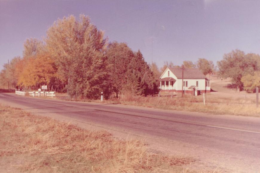 Old color photograph showing the Carlson Farm house from the highway.