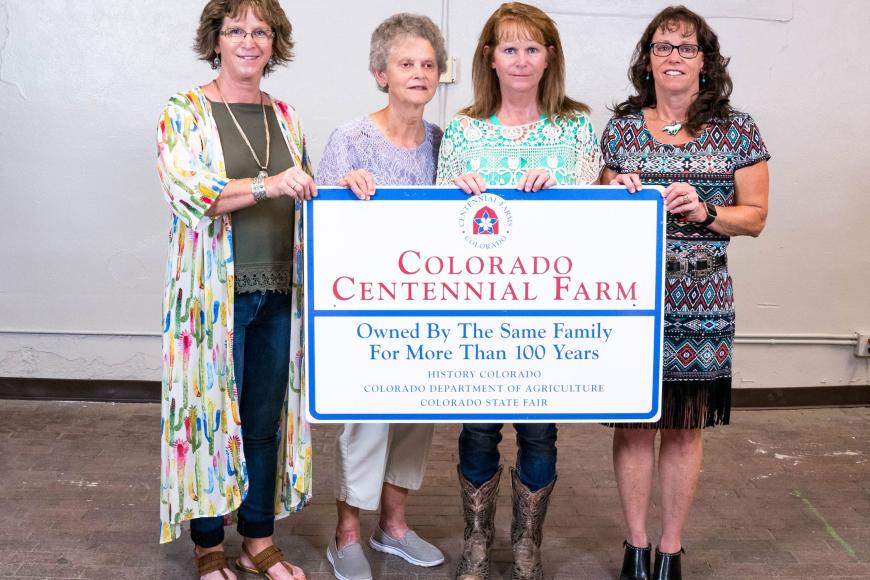 CTL Farm and Ranch family holding their Centennial Farms & Ranches sign.