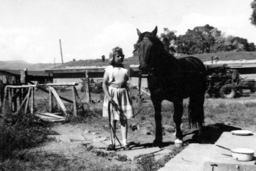 A girl and a horse standing next to some steps, 1954.
