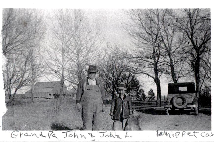 Historic photo showing grandpa John Wyss with grandson John Koch.  A Whippet car is on the right side of the picture.