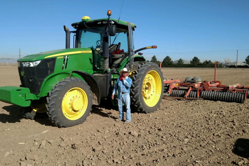 A man stands next to a modern day tractor.