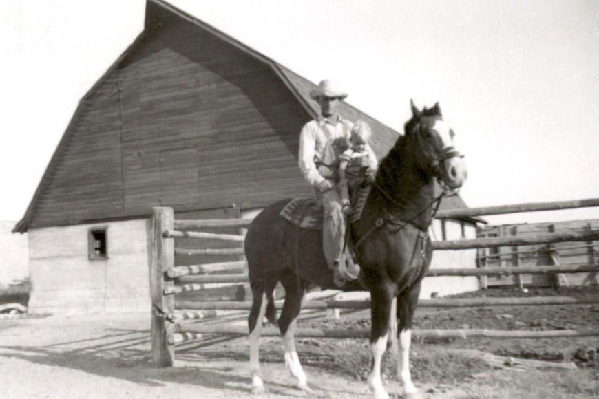 Historic photo of Robert Gates as a small boy, with his father Alfred, on a horse outside the barn.