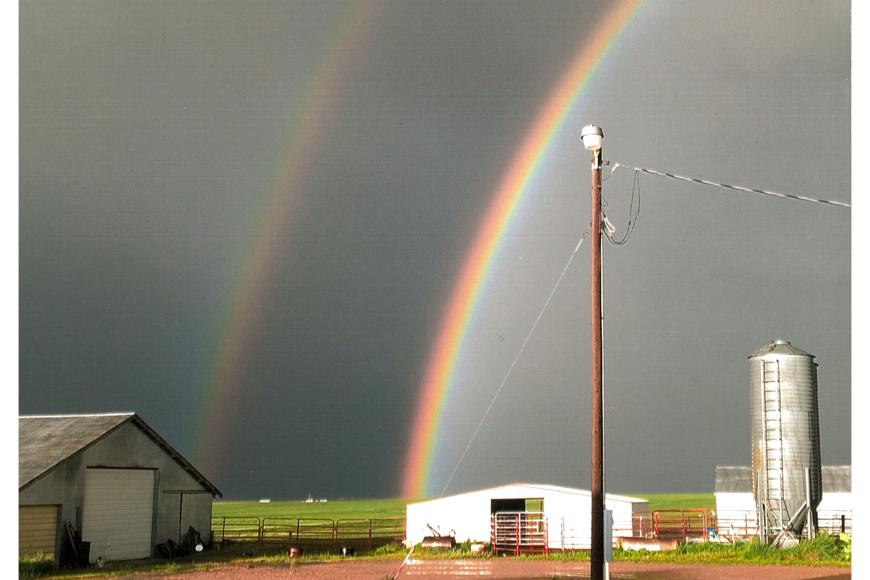 A double rainbow stretches across a gray sky over Fairview Farms.