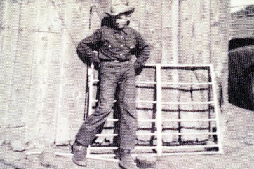 Historic image of a cowboy standing in front of a shed on the Vallejos Ranch.  The shed was built in the 1930s.