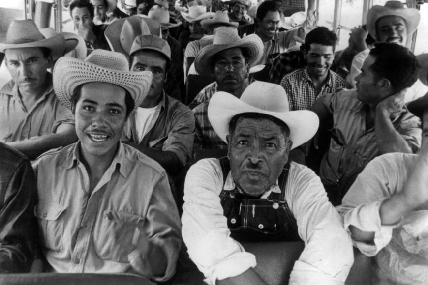 Mexican migrant workers sit in a bus near Fort Lupton (Weld County), Colorado. They wear wide-brimmed hats. One man wears overalls.