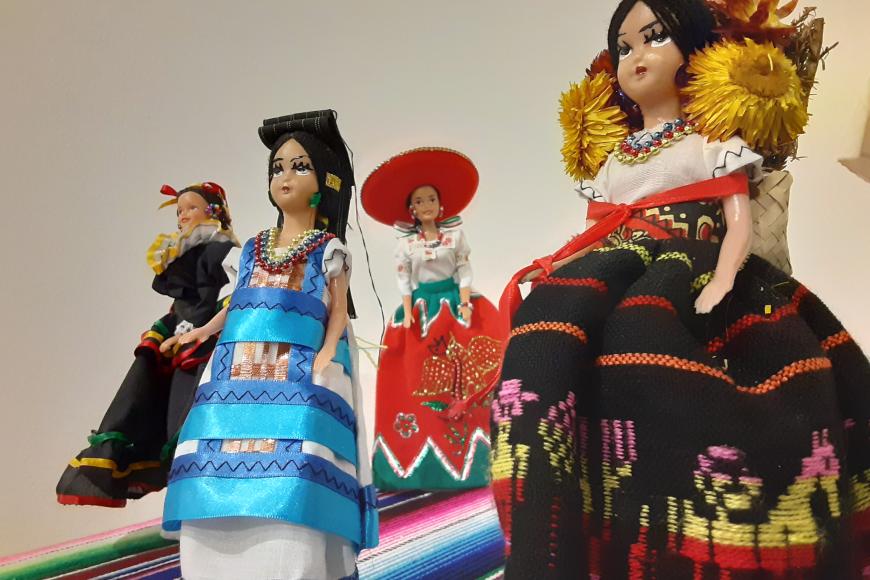 A small collection of dolls wearing several varieties of traditional Mexican ballet folklorico costumes.