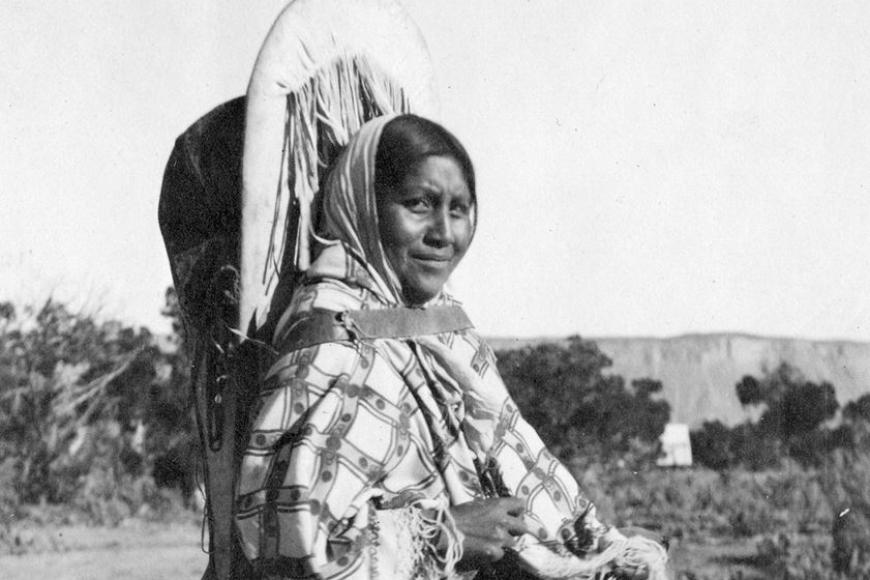 Ute woman carrying her baby in a traditional hide cradleboard, 1895-1905.