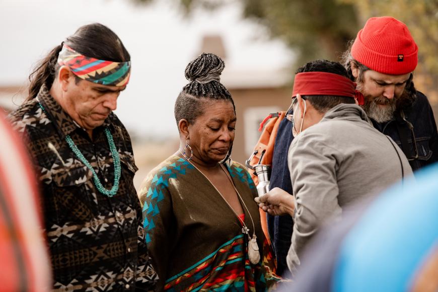 A group of people of many ethnicities and races participate in a Native American tree planting ceremony at Fort Garland in the summer of 2021.