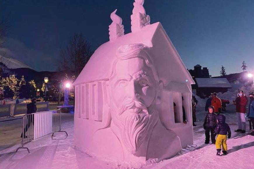 A snow sculpture of a house, with one corner carved into the face of a bearded man: Barney L. Ford