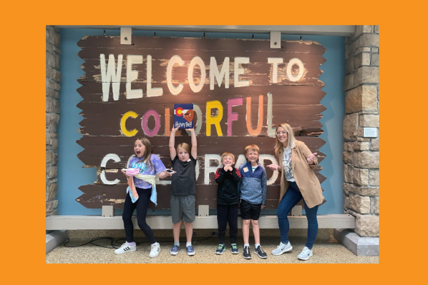 Four children and their mom standing in front of "Welcome to Colorful Colorado" sign