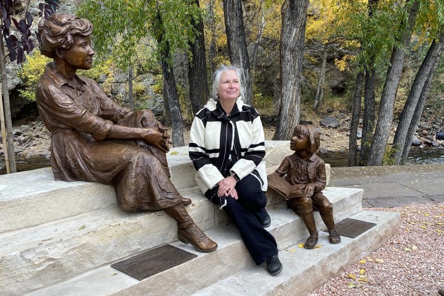 Jane DeDecker sitting with two of her statues.