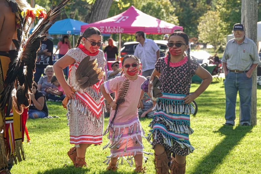 Three young Indigenous women in traditional dress at the Pueblo multicultural festival.