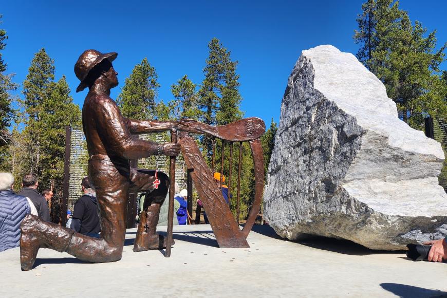 A perspective of the centerpiece of the Leadville Miners' Memorial, which depicts a man with a pick, kneeling at an Irish harp.
