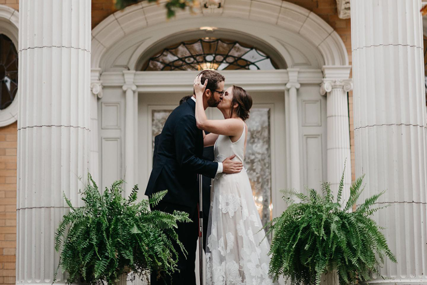 A newlywed couple kiss on Grant-Humphreys mansion steps.