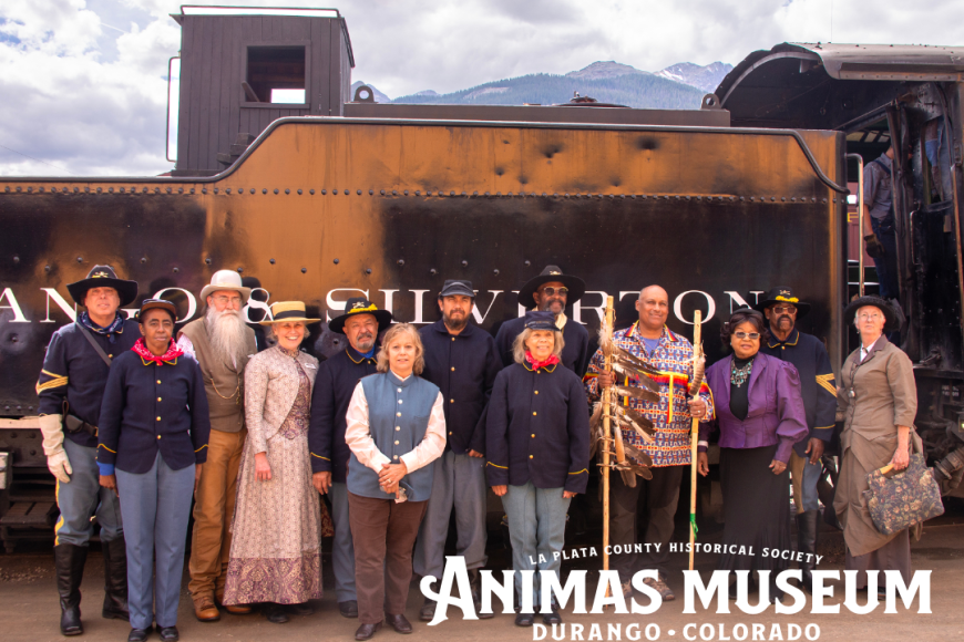 A group of people in civil war era clothing pose in front of the Durango Silverton train.