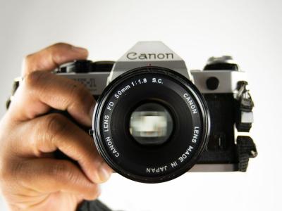 A Canon-brand camera being held by a person's hand. The person is not visible.