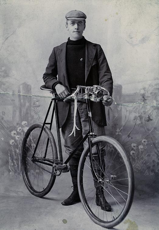 A studio portrait of Fred Payne Clatworthy with a bicycle