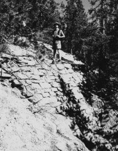 Historic black-and-white image showing a hiker standing on East Longs Peak Trail, in the Estes Park vicinity, Boulder/Larimer Counties. The trail was listed in the National Register in 2007.