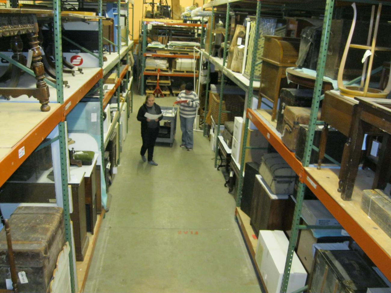 Two HC employees stand in the middle of two rows of collection items.