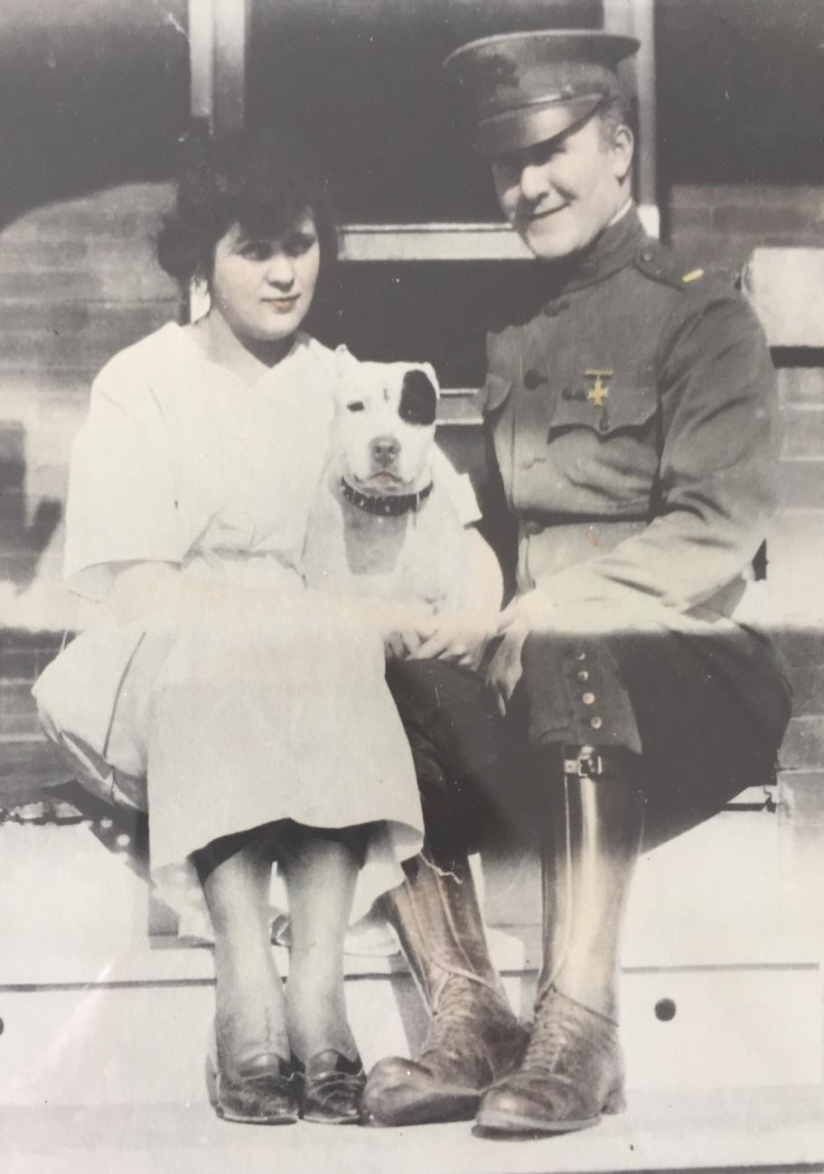 Margaret Gessing and Joe Bona in his World War One uniform sit with a dog between them.
